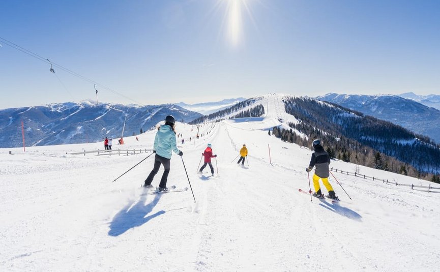 Skifahrer auf schneebedeckter Piste bei sonnigem Wintertag in den Bergen