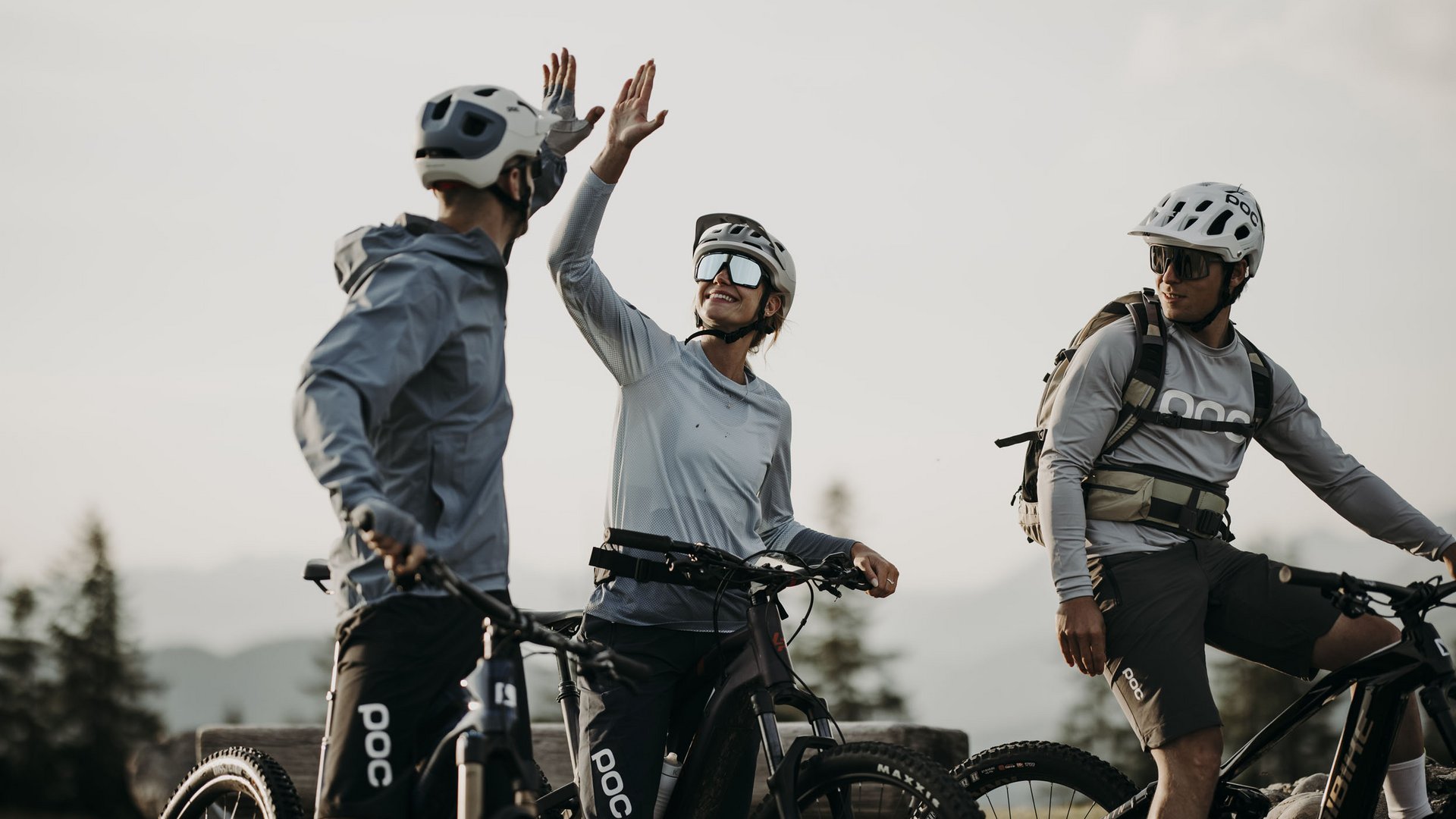 MTB in der DNA: Bikesommer im DIPS&DROPS © Matthias Warter Drei Radfahrer in Schutzhelmen geben sich Highfive beim Stopp im Freien