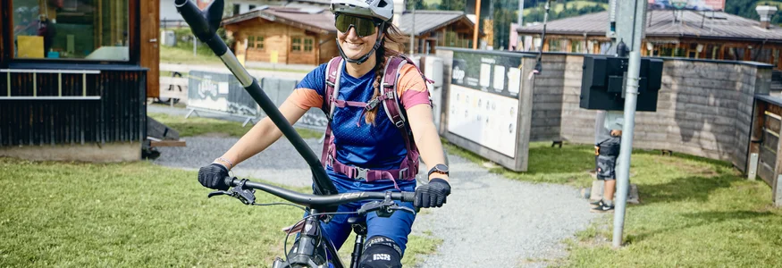 Frau mit Helm und Schutzkleidung auf Mountainbike in Berglandschaft