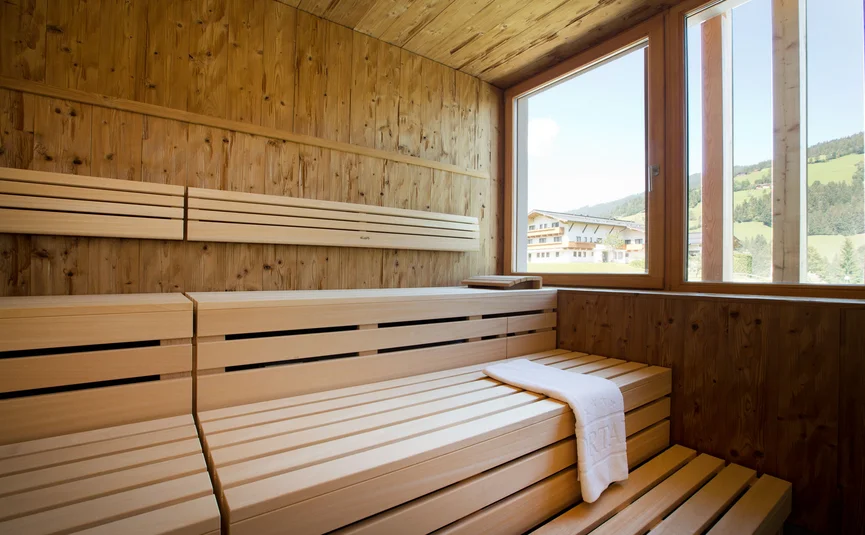 Sauna mit Holzbank und Fenster mit Blick auf grüne Landschaft