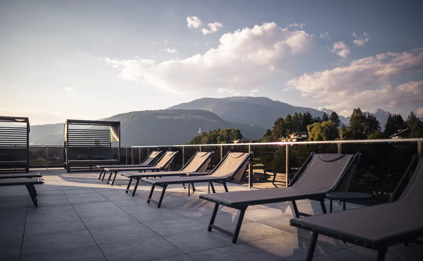 Empty loungers on terrace with mountain view at sunset
