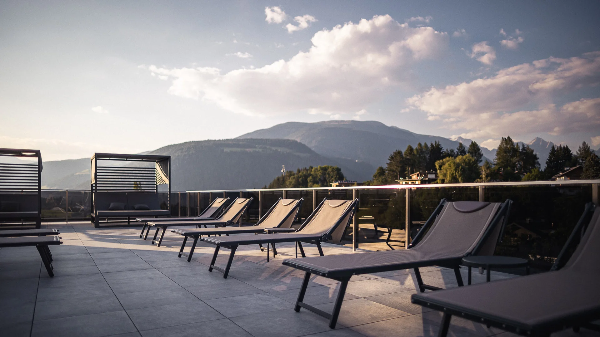 Leere Liegestühle auf Terrasse mit Bergblick bei Sonnenuntergang