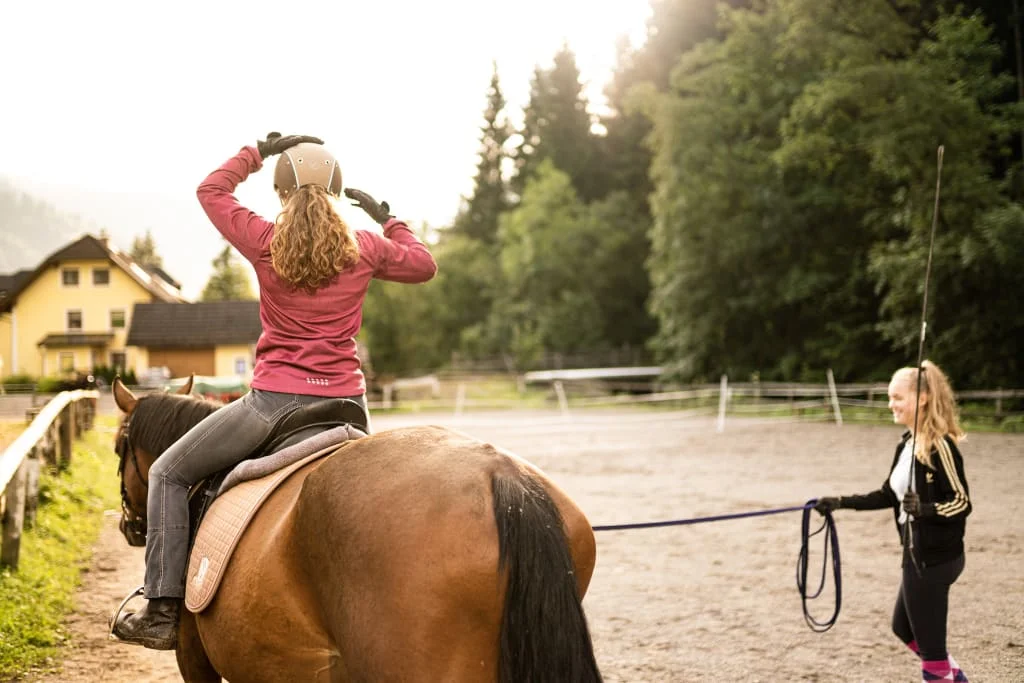 Erstes Reiterglück / 3 Nächte Ruiter doet helm op terwijl instructeur paard leidt