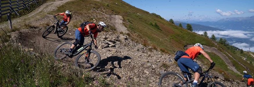 Mountainbiker fahren auf einem kurvigen Bergtrail bei klarem Himmel