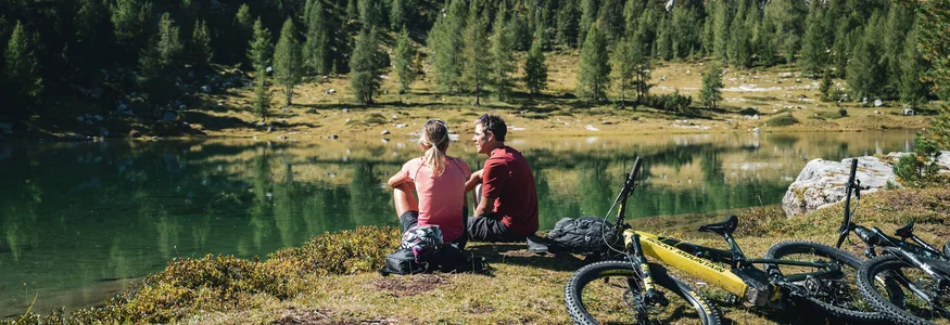 Zwei Radfahrer sitzen am See in den Bergen und genießen die Aussicht