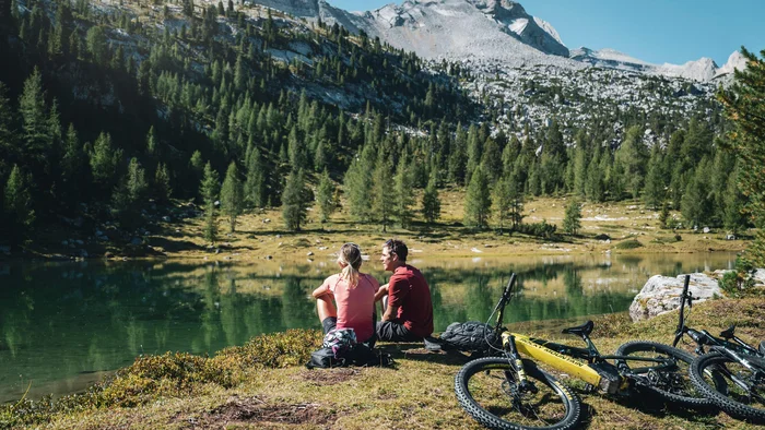 Zwei Radfahrer sitzen am See in den Bergen und genießen die Aussicht