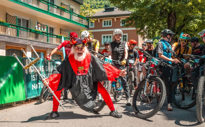 Nockbike-Trophy Hit Man in duivelskostuum poseert voor fietsers bij een evenement buiten