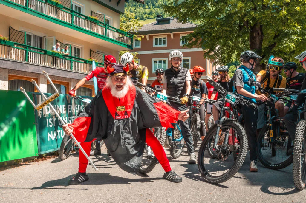 Ein Mann im Teufelskostüm posiert vor Radfahrern bei einer Veranstaltung