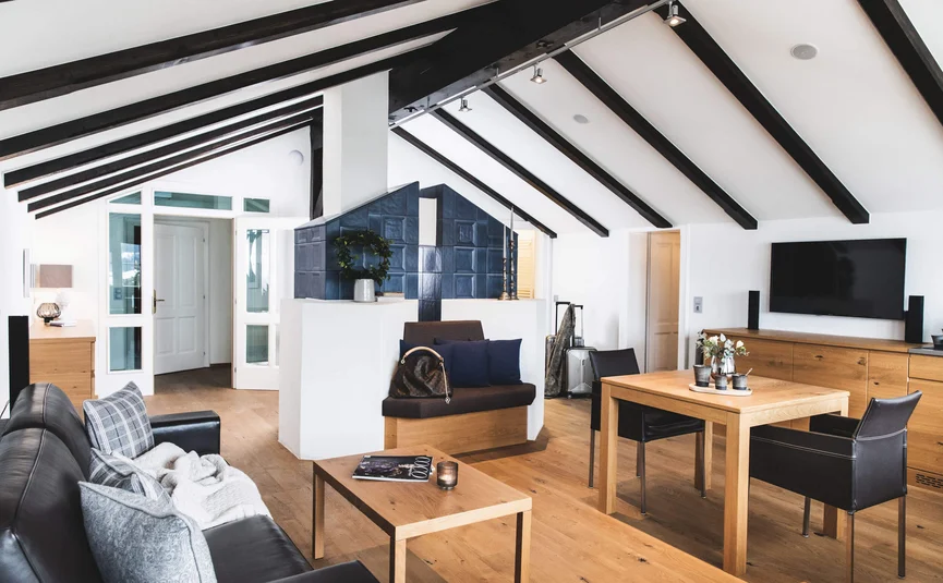 Modernes Wohnzimmer mit natürlichem Holz und schwarzen Akzenten im Dachgeschoss