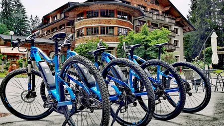 Was steckt hinter dem Umweltengagement von Bikehotels? © Ribno Alpine Resort - Katarina Strgar Vier blaue E-Mountainbikes vor einem Hotel in den Bergen