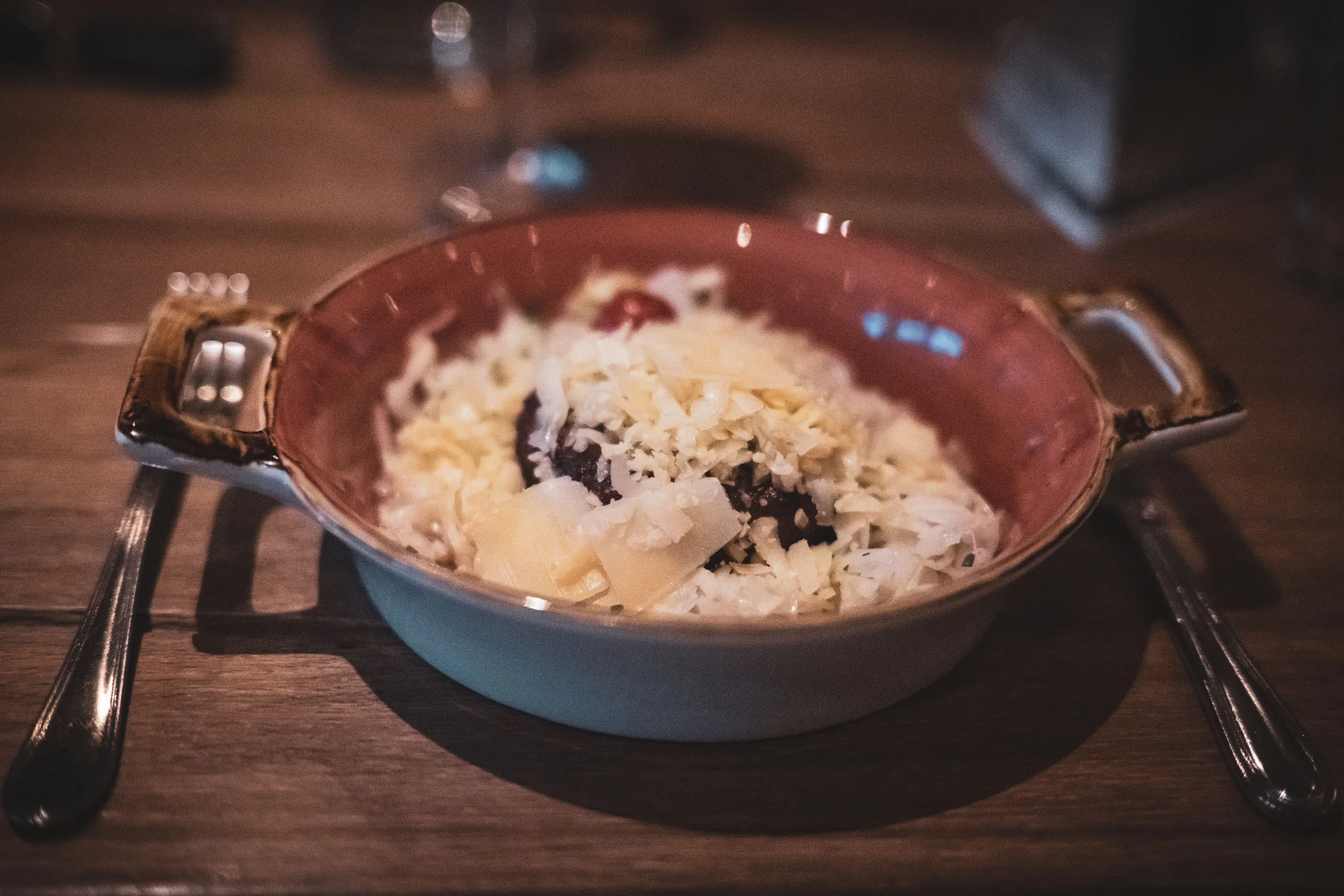 Schüssel mit Reisbällchen und Käse auf Holzuntergrund