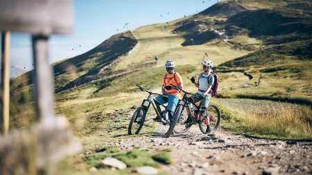 Unterwegs in Österreichs größter Bikeregion © Tobias Köhler Zwei Mountainbiker mit Helmen pausieren auf einem Bergweg bei sonnigem Wetter