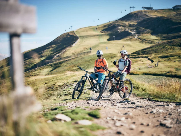 Unterwegs in Österreichs größter Bikeregion © Tobias Köhler Zwei Mountainbiker mit Helmen pausieren auf einem Bergweg bei sonnigem Wetter
