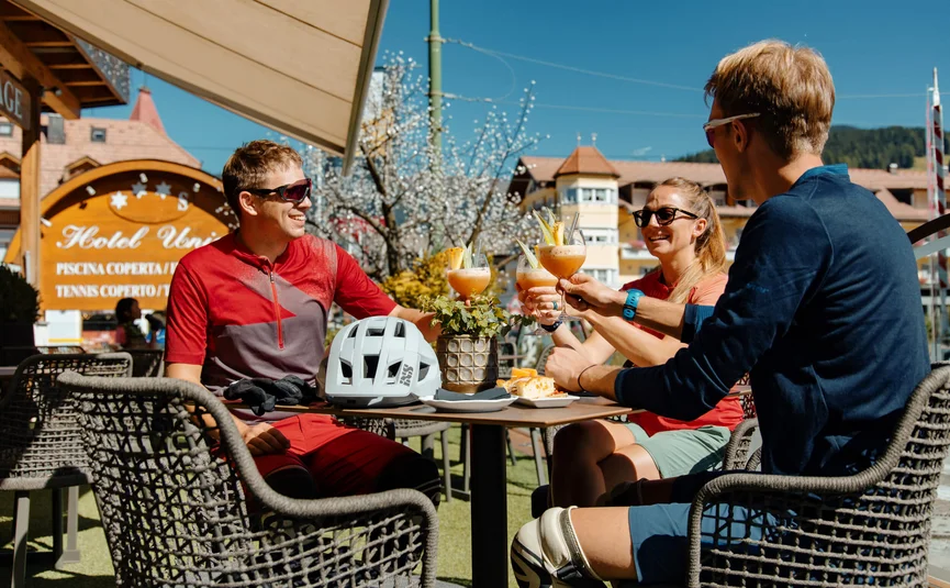 Drie fietsers proosten met drankjes en ontspannen buiten aan een tafel