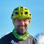Mann mit grünem Helm auf Mountainbike vor Bergkulisse