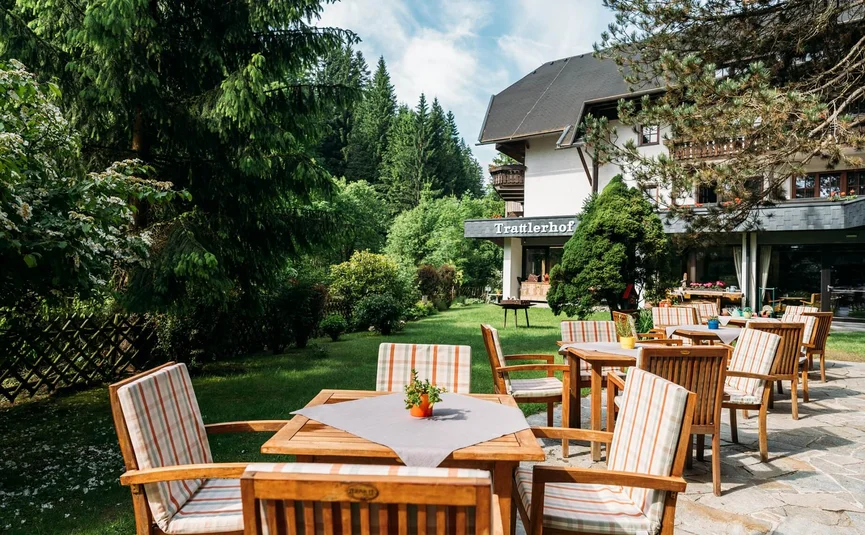 Gemütlicher Außenbereich mit Tischen und Stühlen vor einem Gasthaus im Grünen