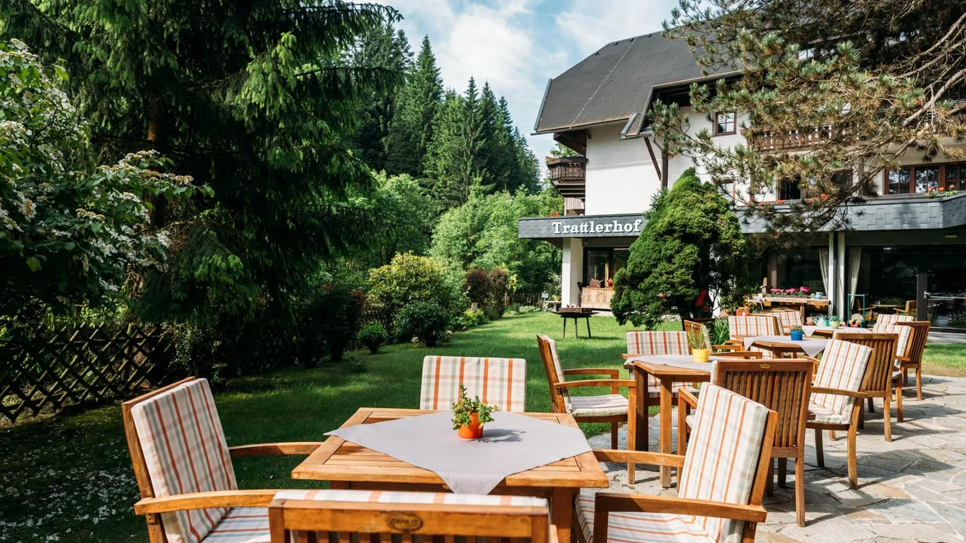 Gemütlicher Außenbereich mit Tischen und Stühlen vor einem Gasthaus im Grünen