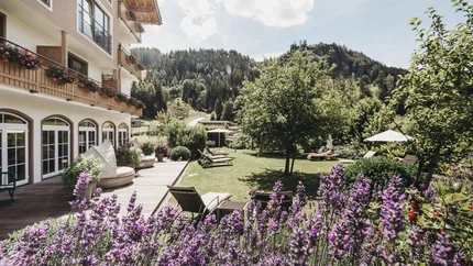 Hotelgarten mit Lavendel, Liegestühlen und Berglandschaft im Hintergrund
