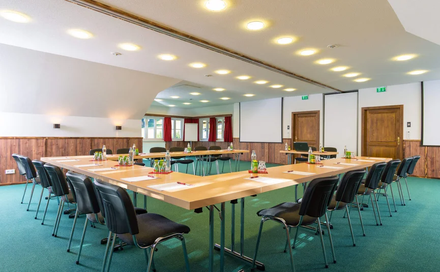 Vergaderruimte met U-vormige tafels en klaargelegde benodigdheden