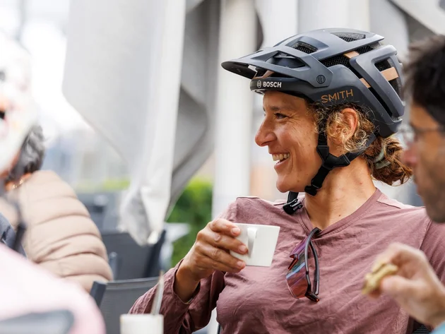Das war die bike festa Südtirol in Brixen © Brixen_Tourismus - bike festa Südtrirol 2026 Radfahrerin mit Helm trinkt mit Freunden in einem Straßencafé