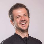 Mann mit Mountainbike-Urlaub-Shirt lächelnd vor neutralem Hintergrund