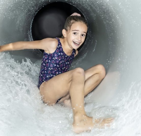 Girl in swimsuit happily sliding down a water slide