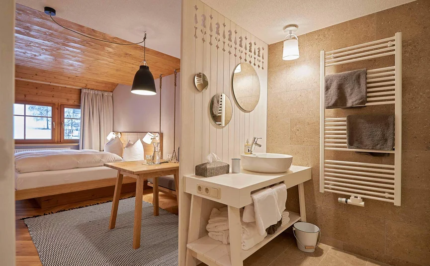 Gezellige slaapkamer met wastafel en badkamer gescheiden door houten scheidingswand