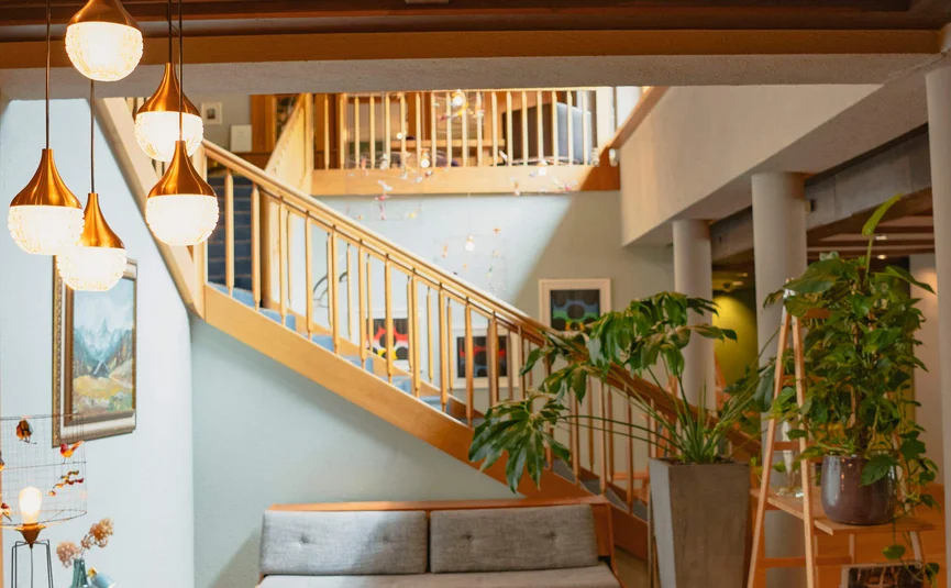 Modernes Wohnzimmer mit grauer Couch, Holzmöbeln und hängenden Lampen