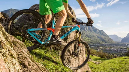 Mountainbiker fahren auf einem felsigen Abhang bei sonnigem Wetter.