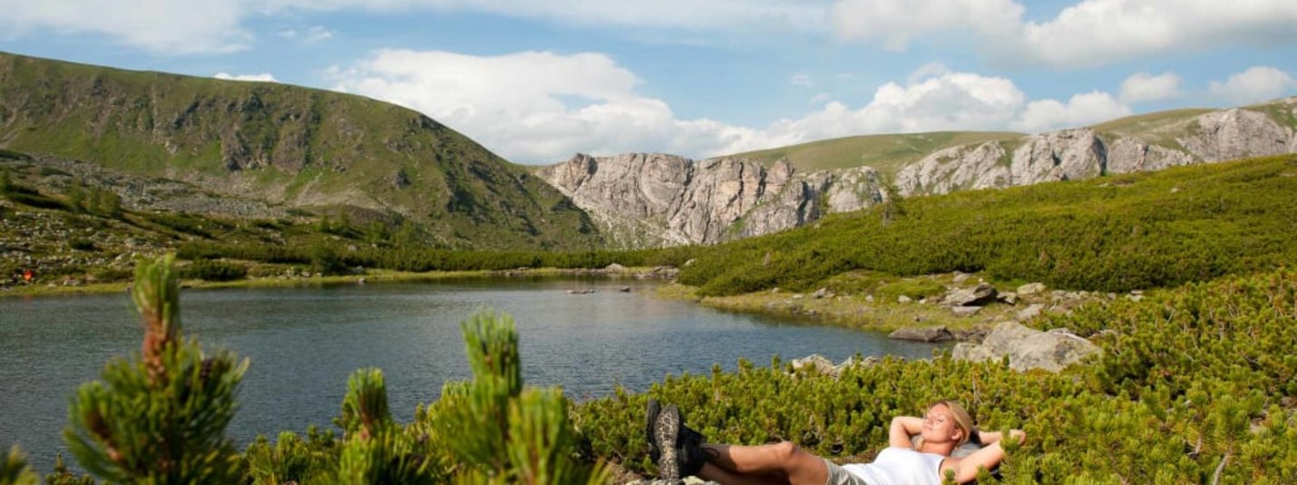 Wanderlust in den Nockbergen Vrouw ontspant bij een meer omgeven door bergen en groene natuur