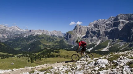 Mountainbiker fährt auf einem felsigen Pfad in den Bergen bei klarem Himmel