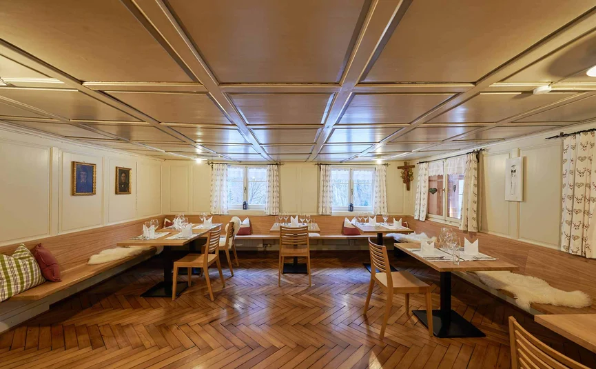 Gezellige eetkamer met houten tafels, stoelen en ramen met gordijnen