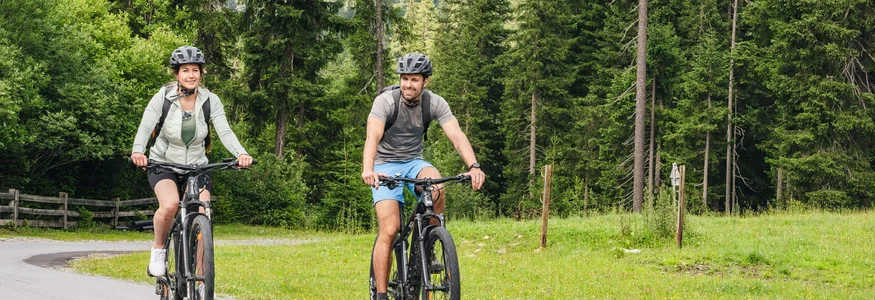 Man and woman riding mountain bikes on scenic forest mountain road