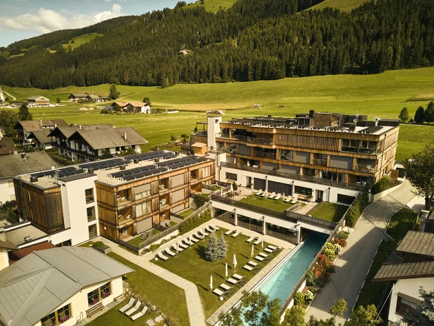 Was steckt hinter dem Umweltengagement von Bikehotels? © David Rasche Hotelanlage mit Schwimmbad und Liegestühlen in grüner Berglandschaft