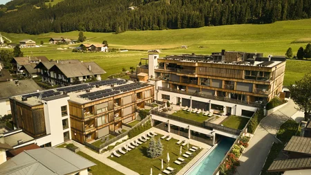 Was steckt hinter dem Umweltengagement von Bikehotels? © David Rasche Hotelanlage mit Schwimmbad und Liegestühlen in grüner Berglandschaft