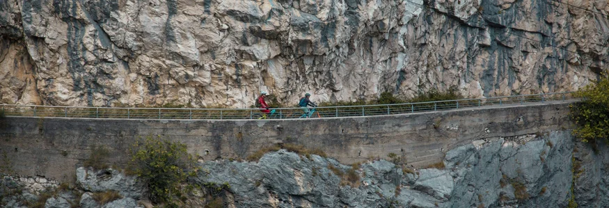 Two cyclists on narrow path along steep rocky cliff