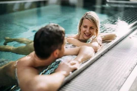 Tesla Nockberge Experience Drive - 3 nights Couple relaxing in pool holding hands and smiling