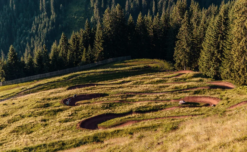 Hahnenkamm Trail © David Karg Mountainbike-Trail mit engen Kurven auf einer Bergwiese neben Wald