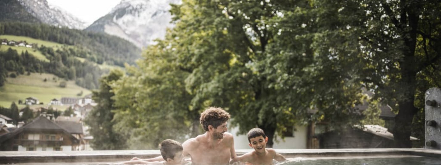 Vater und zwei Kinder genießen heißen Pool mit Bergblick