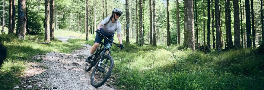 Vrouw mountainbiken op bospad met helm en zonnebril