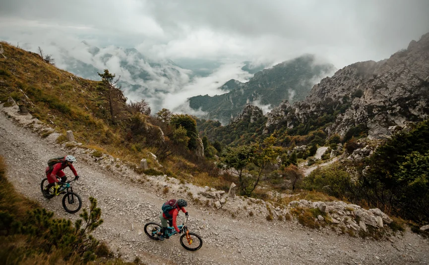 Twee mountainbikers op rotsachtig bergpad bij bewolkte lucht
