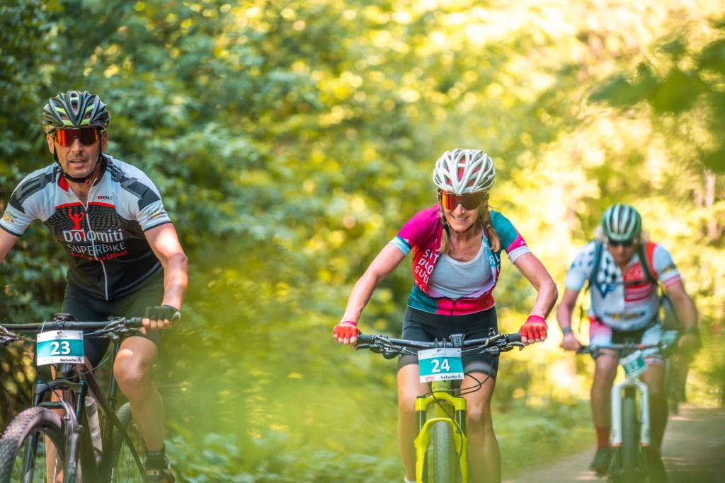 Group of cyclists riding on forest trail in sunny weather