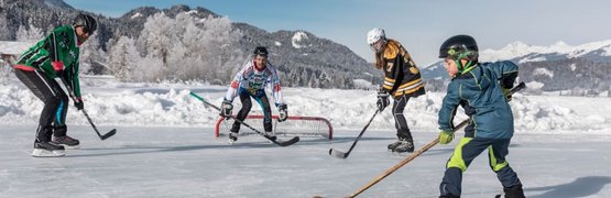 Kinderen spelen ijshockey op bevroren meer in besneeuwd berggebied