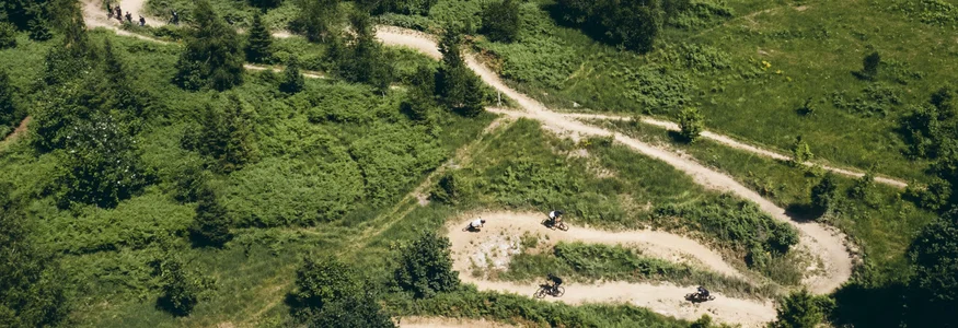 Smalle kronkelige bospaadjes met mountainbikers die naar beneden rijden