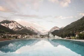Infinity pool overlooking Alps and village in the valley