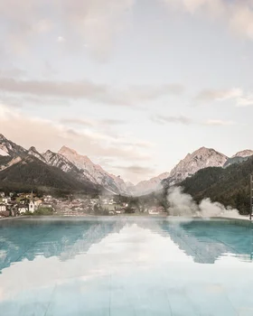 Infinity-Pool mit Blick auf Alpen und Dorf im Tal
