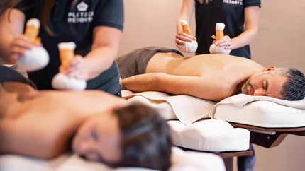 Zwei Personen erhalten Kräuterstempelmassagen in einem Spa