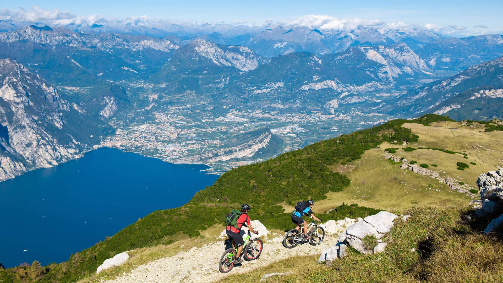 Zwei Mountainbiker auf Bergweg mit Blick auf See und Berge