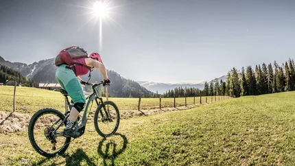 Vrouw mountainbiken op groen gras onder zonnige berglucht