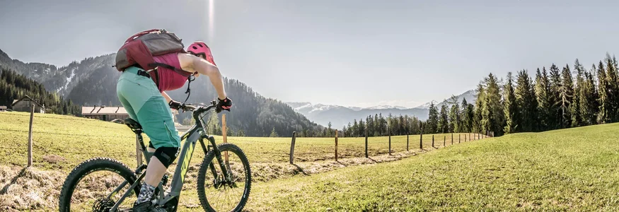 Vrouw mountainbiken op groen gras onder zonnige berglucht